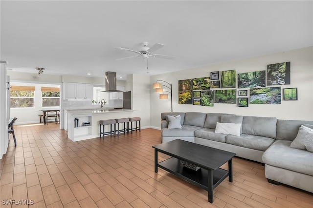 living area with light wood-style flooring, baseboards, and ceiling fan