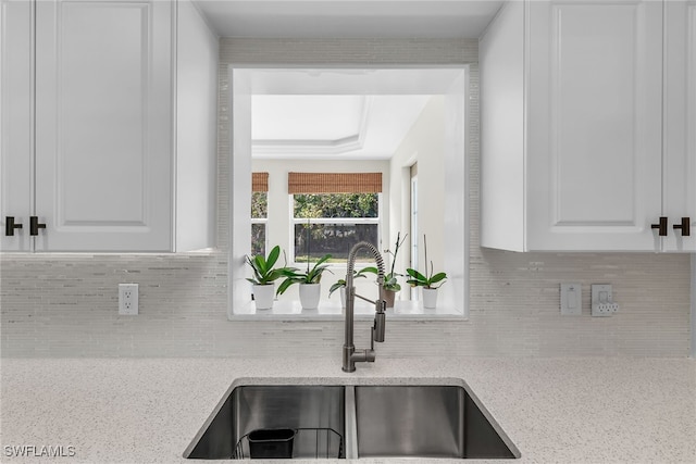 kitchen featuring backsplash, a sink, and white cabinets