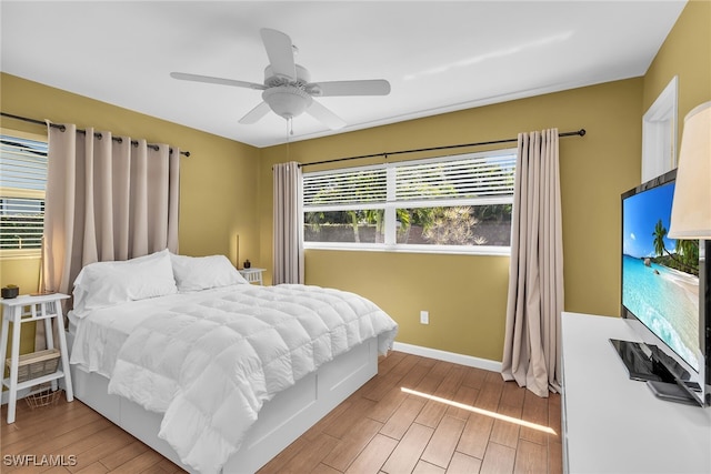 bedroom with ceiling fan, light wood finished floors, and baseboards