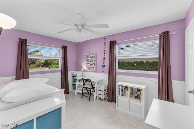 bedroom featuring ceiling fan and wainscoting