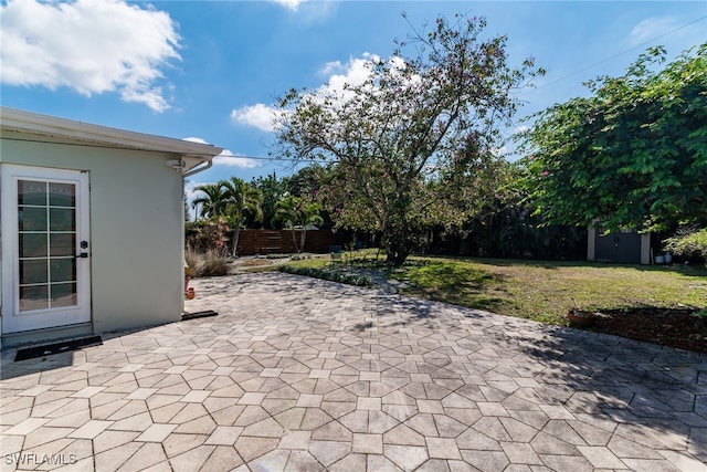 view of patio with an outbuilding, a storage unit, and fence