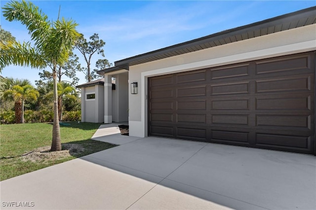 view of front facade with a garage, concrete driveway, a front yard, and stucco siding