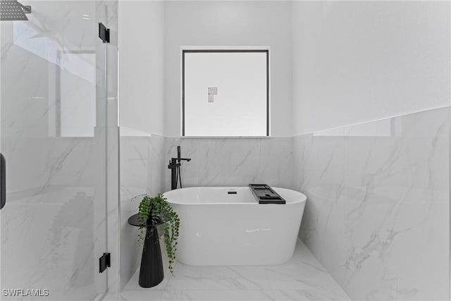 bathroom featuring marble finish floor, a freestanding bath, and a shower stall