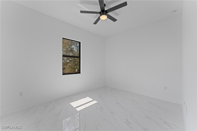 unfurnished room featuring ceiling fan, marble finish floor, and baseboards