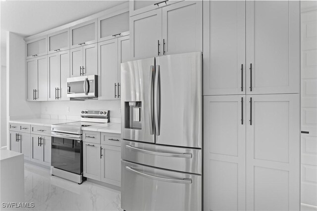 kitchen featuring stainless steel appliances, marble finish floor, light countertops, and glass insert cabinets