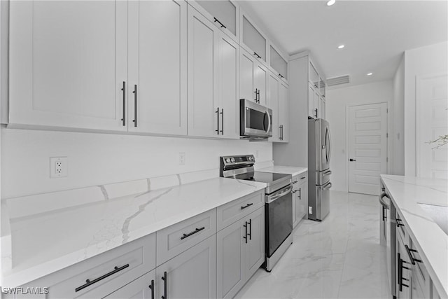 kitchen with marble finish floor, stainless steel appliances, recessed lighting, glass insert cabinets, and light stone countertops