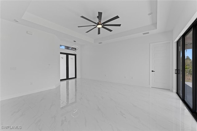 empty room featuring a tray ceiling, marble finish floor, and visible vents