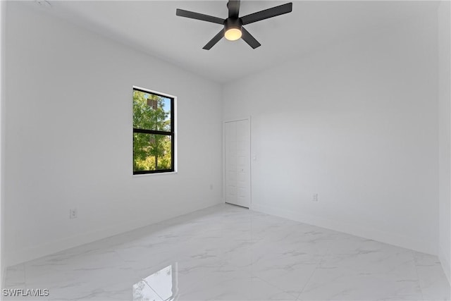 spare room featuring marble finish floor, baseboards, and a ceiling fan