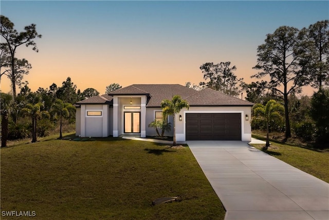 view of front of house featuring a garage, driveway, a front lawn, and stucco siding