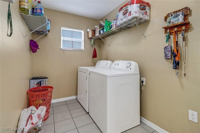 washroom with laundry area, washing machine and dryer, light tile patterned floors, and baseboards