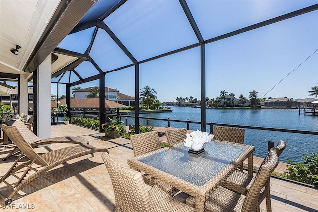 view of patio featuring glass enclosure, outdoor dining space, and a water view