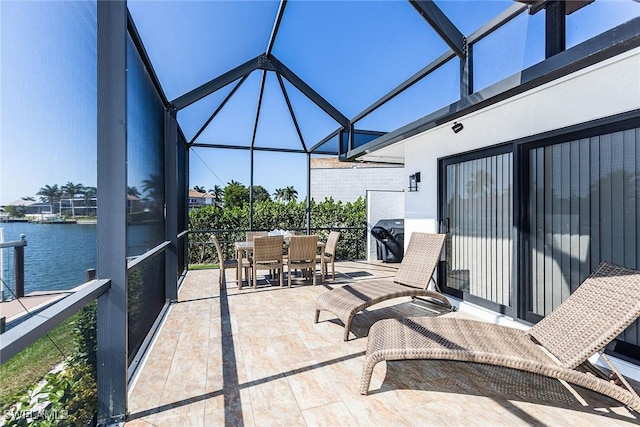 view of patio / terrace with a water view, glass enclosure, and outdoor dining space