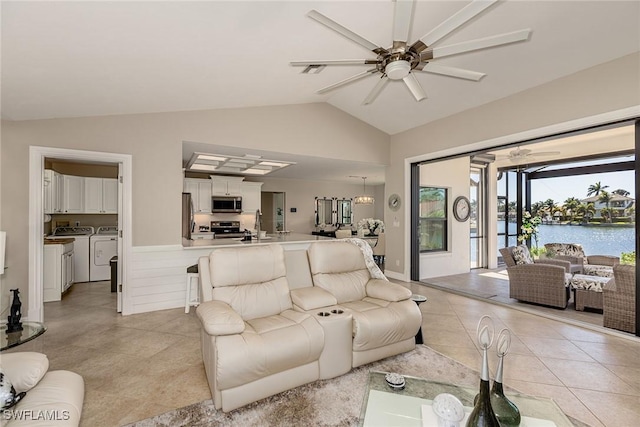 living room featuring washer and clothes dryer, visible vents, light tile patterned flooring, vaulted ceiling, and ceiling fan