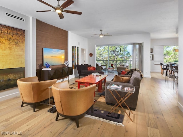 living room featuring light wood-style floors, visible vents, ceiling fan, and baseboards