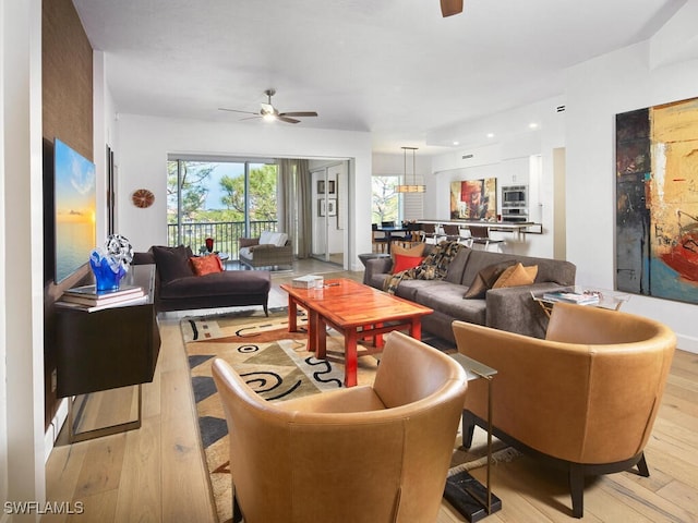 living area featuring light wood-style floors and a ceiling fan