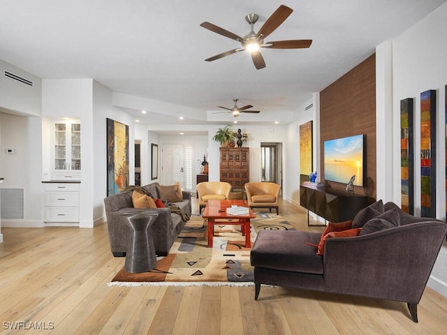 living room with baseboards, visible vents, and light wood finished floors