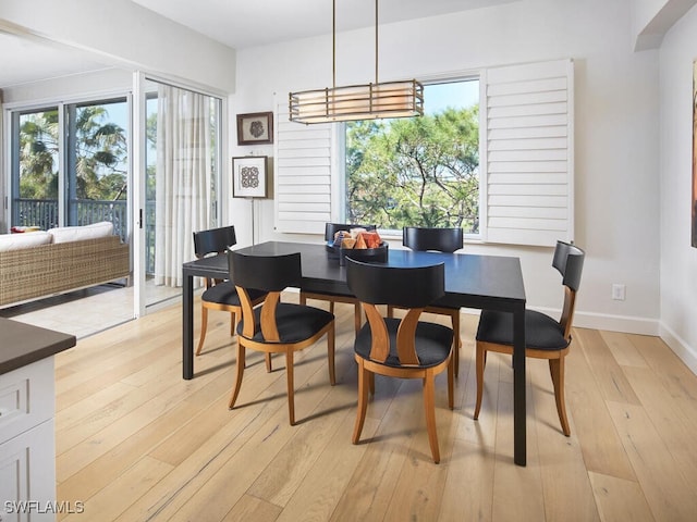 dining area with arched walkways, light wood-style flooring, and baseboards