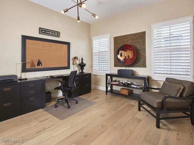 home office featuring light wood-type flooring, baseboards, and a chandelier