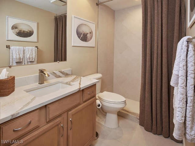 bathroom with toilet, a tile shower, and vanity