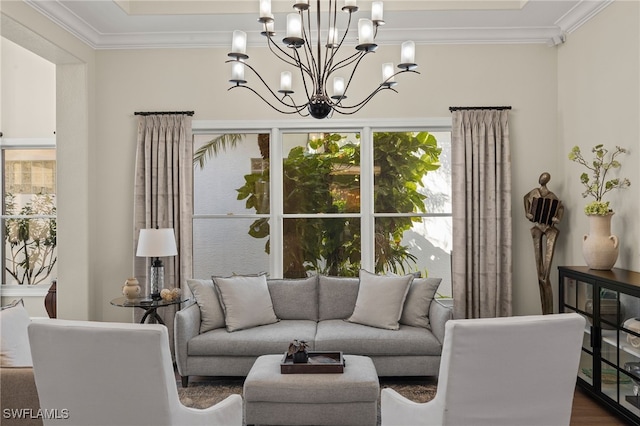 living area with dark wood-style floors, a notable chandelier, and ornamental molding