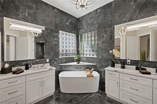 bathroom with a freestanding tub, two vanities, a sink, marble finish floor, and a chandelier