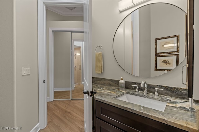 bathroom with vanity, crown molding, wood finished floors, and baseboards