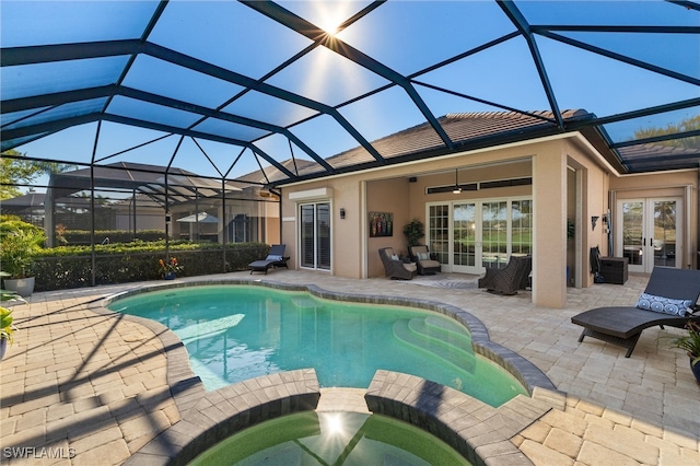 view of swimming pool featuring glass enclosure, a patio area, french doors, and a pool with connected hot tub