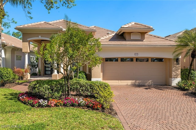 view of front facade featuring stucco siding, decorative driveway, a garage, and a tile roof