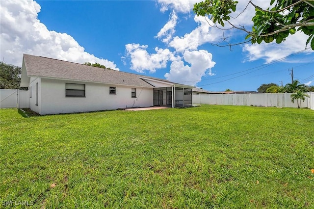 rear view of house featuring a lawn, a fenced backyard, a sunroom, and stucco siding