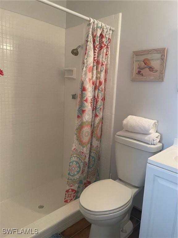 bathroom featuring vanity, a shower stall, and toilet