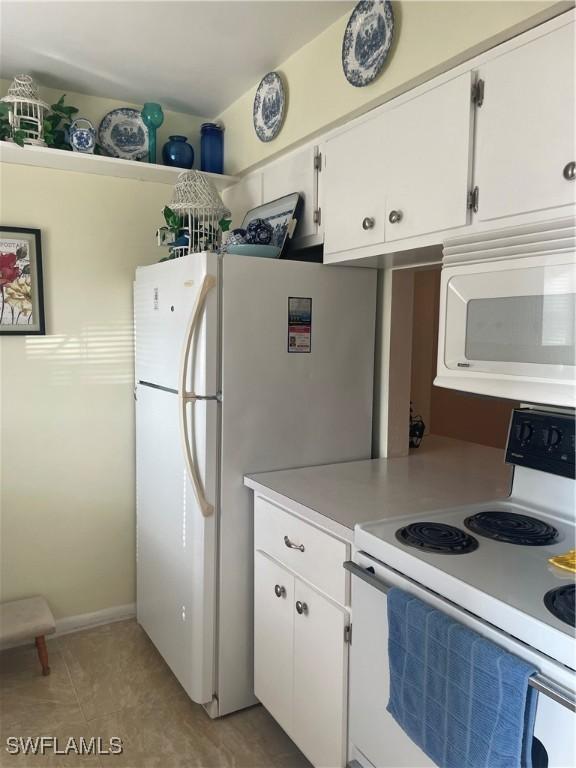 kitchen featuring white appliances, white cabinetry, light countertops, and light tile patterned flooring