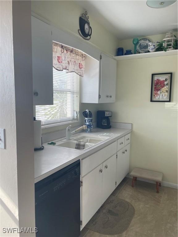 kitchen with dishwasher, light countertops, a sink, and white cabinets