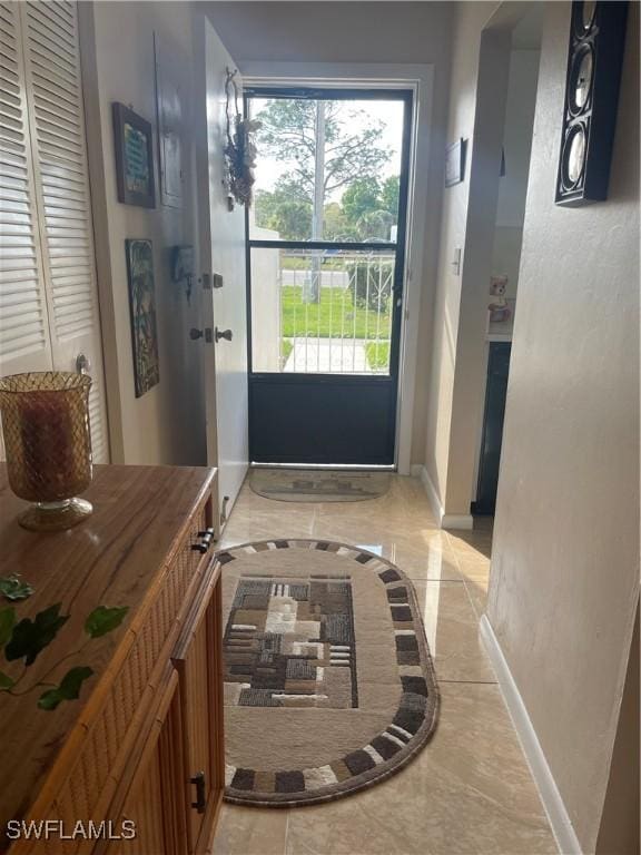 doorway to outside featuring marble finish floor and baseboards