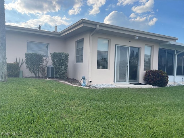 view of side of home featuring central air condition unit, a yard, and stucco siding