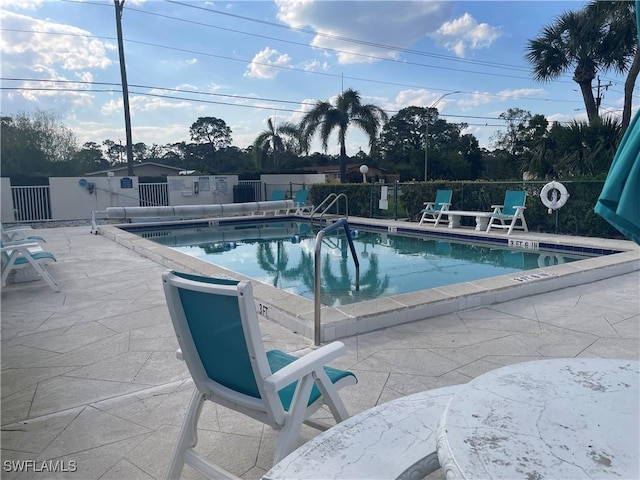 community pool with a patio area and fence