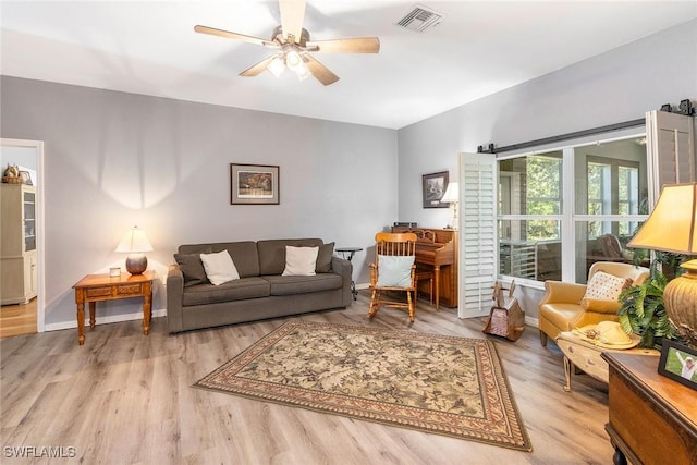 living area with a ceiling fan, visible vents, baseboards, and wood finished floors