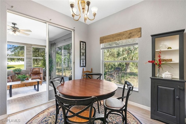 dining space with light wood-type flooring, baseboards, and ceiling fan with notable chandelier