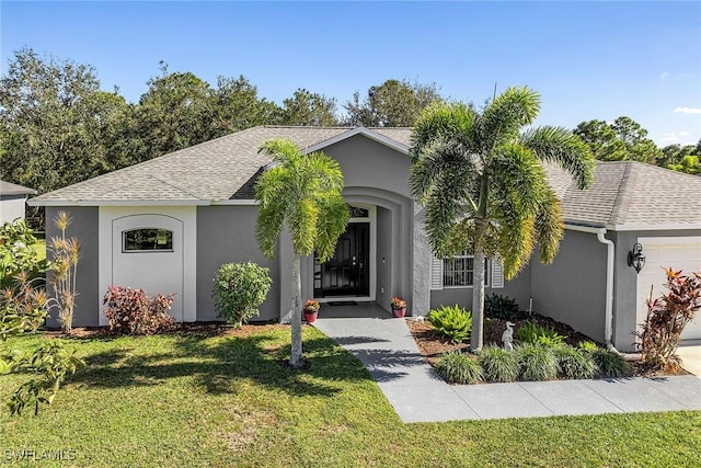 ranch-style home featuring a front lawn, a shingled roof, an attached garage, and stucco siding