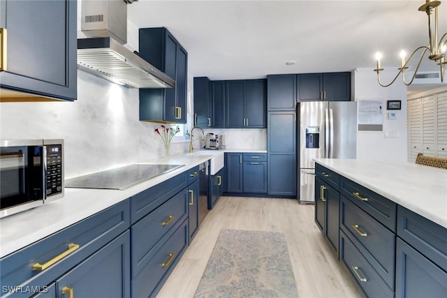 kitchen featuring black electric stovetop, a sink, wall chimney range hood, light wood-type flooring, and stainless steel fridge with ice dispenser