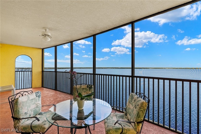 sunroom / solarium featuring a water view and a ceiling fan