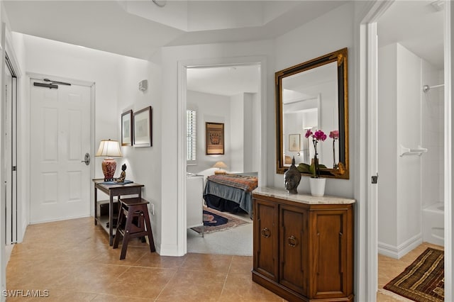 hall featuring light tile patterned floors and baseboards