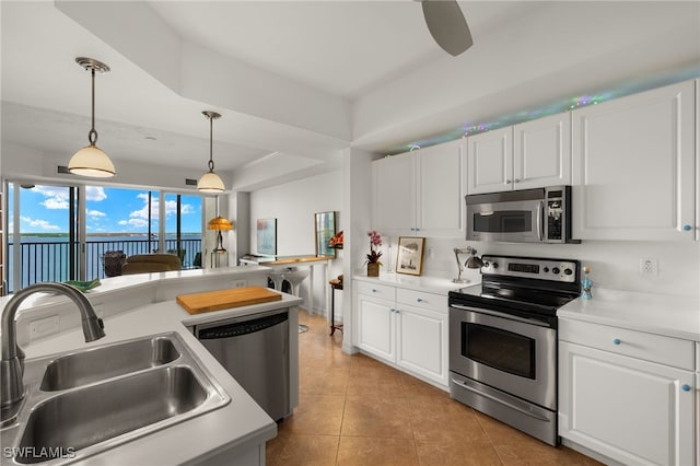 kitchen with stainless steel appliances, white cabinetry, a sink, and hanging light fixtures