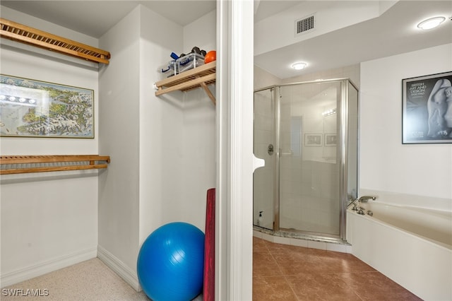 bathroom featuring visible vents, baseboards, a spacious closet, a bath, and a stall shower