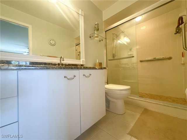 bathroom featuring vanity, a shower stall, toilet, and tile patterned floors