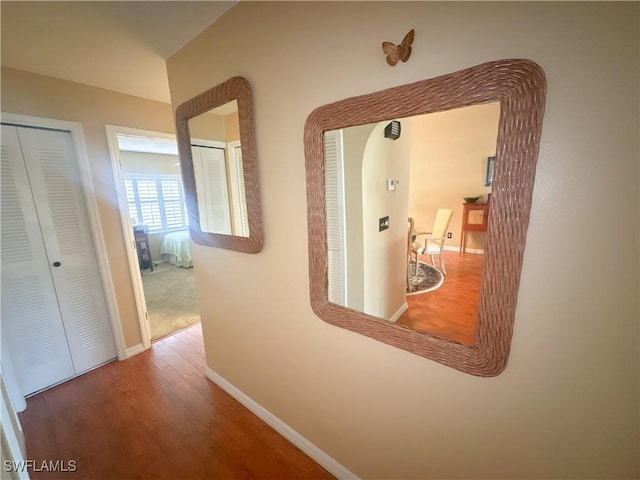 corridor with baseboards and wood finished floors