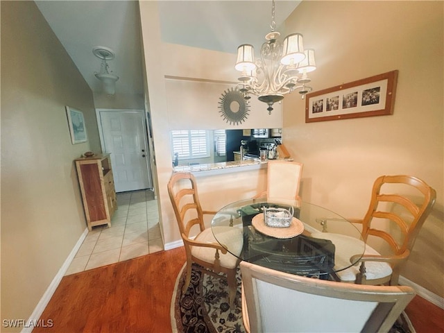 dining space featuring lofted ceiling, light wood-style floors, baseboards, and an inviting chandelier