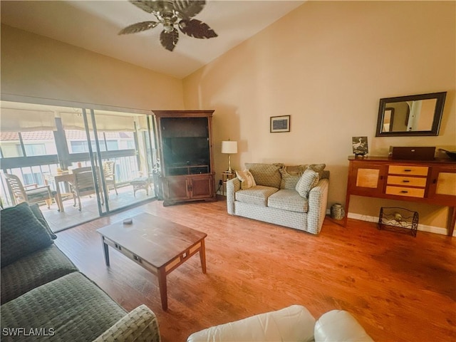 living area featuring ceiling fan, high vaulted ceiling, light wood-type flooring, and baseboards