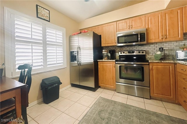 kitchen featuring appliances with stainless steel finishes, light stone counters, decorative backsplash, and light tile patterned floors