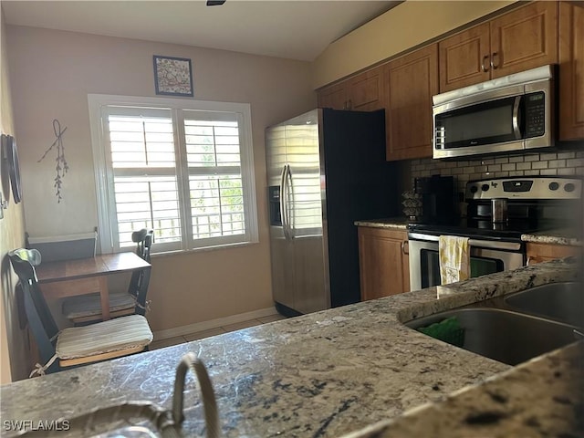11570 Caravel Cir Unit 2022, Fort Myers, FL 33908 - kitchen featuring stainless steel appliances, brown cabinets, light stone countertops, and tile patterned flooring