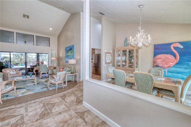 interior space featuring high vaulted ceiling, visible vents, a notable chandelier, and baseboards